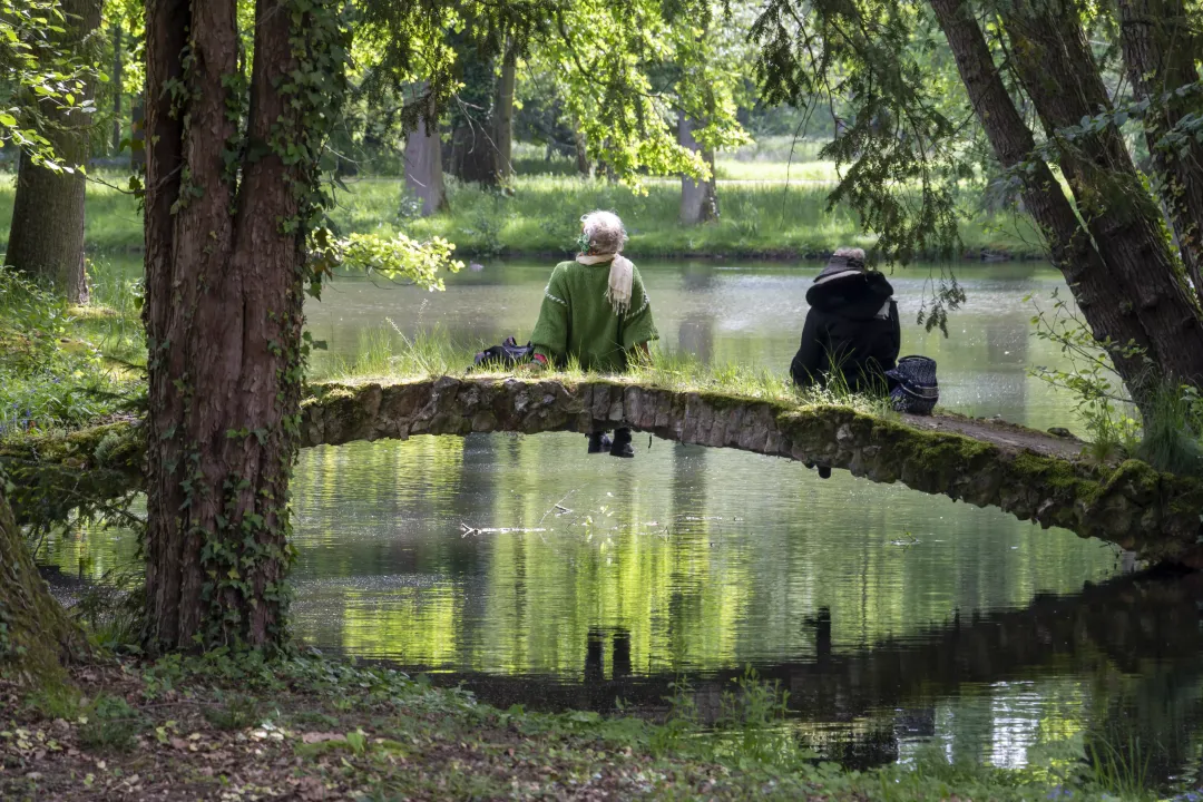 Deux personnes se prélassent sur un pont qui surplombe un étang dans le parc de Schoppenwihr